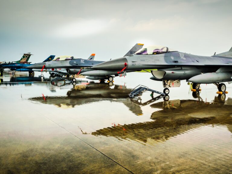 US military fighter jets at air show. three jets in view with fresh rain showing reflection on the cement.