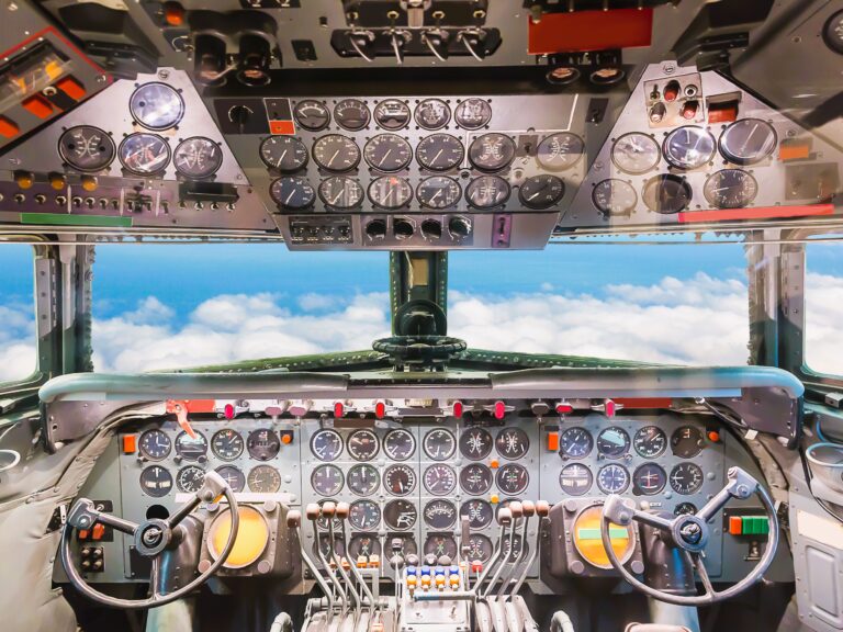 inside of airplane cockpit with clouds ahead and full view of avionics system