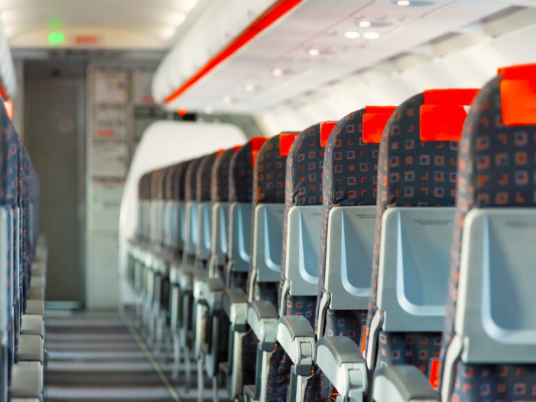 inside of single aisle aircraft with black and red empty seats